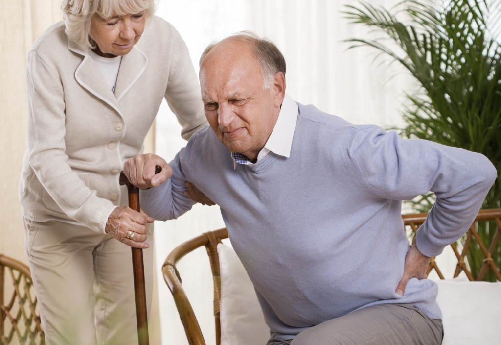 Woman helping an elderly man having a back pain